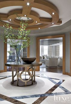 a living room filled with furniture and a plant on top of a round wooden table