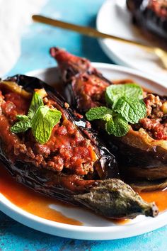 stuffed eggplant peppers with tomato sauce and mint garnish on a plate