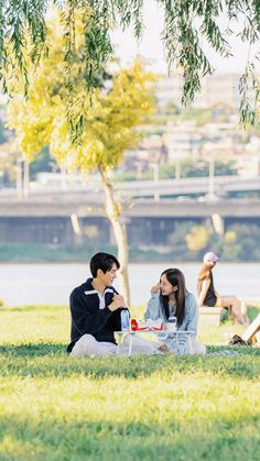 two people are sitting on the grass eating