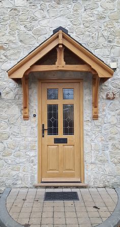 a wooden door on the side of a stone building with a brick walkway in front of it