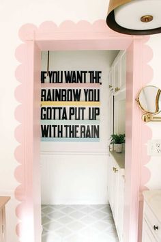 an open door leading to a bathroom with pink trim and black lettering on the wall