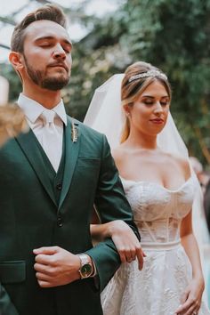 a man in a green suit standing next to a woman wearing a white dress and veil