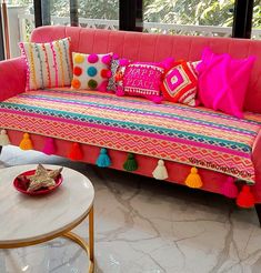 a living room with a pink couch and colorful pillows on top of it's back