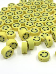 yellow smiley face beads with black eyes on white background, surrounded by smaller yellow faces