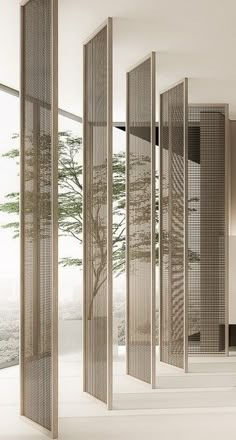 a room divider in the middle of an empty room with trees and windows behind it