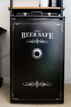 the beer safe cabinet is black with white lettering on it and an ornate border around the door