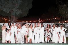 a group of women standing next to each other in front of a pool at night