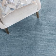 a chair with a pillow on top of it in front of a blue area rug