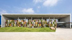 the building is made up of multicolored bookshelves with plants growing on them