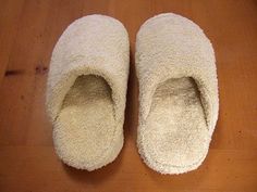 two white slippers sitting on top of a wooden floor