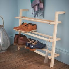 two pairs of shoes are sitting on a wooden shoe rack next to a vase and lamp