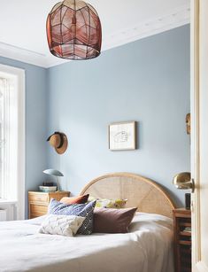 a bed room with a neatly made bed and a basket hanging from the ceiling above it