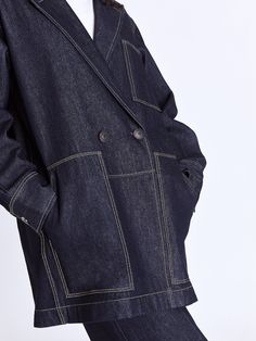 The Raha Denim Jacket brings a laid-back yet sophisticated touch to your workwear collection, featuring real horn buttons and an oversized fit for a modern edge. With practical front patch pockets and a fully functional closure, this unlined jacket effortlessly blends style and functionality. Layer it over a tailored shirt and wide-leg trousers for a polished look that balances comfort with contemporary flair. - Double-breasted, chest and front patch pockets, unlines, horn buttons- CmiA cotton- African Luxury, Contrast Topstitching, Indigo Colour, Workwear Jacket, Dresses Pants, Mini Shirt Dress, Slim Pants, Wide Sleeves, Independent Designers Fashion