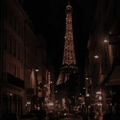 the eiffel tower lit up at night with people walking down the street below