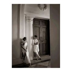 black and white photograph of two women standing next to each other in front of a door