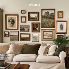 a living room filled with lots of framed pictures on the wall above a white couch