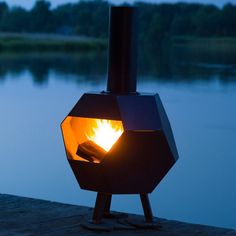 a fire pit sitting on top of a wooden dock next to a body of water