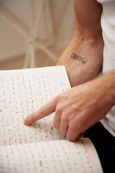 a man with a small tattoo on his arm pointing at a piece of paper that has writing on it