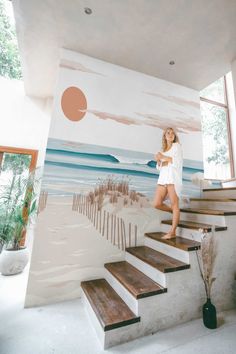 a woman standing on the stairs in front of a painting