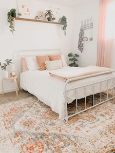 a white bed sitting on top of a rug in a bedroom next to a window