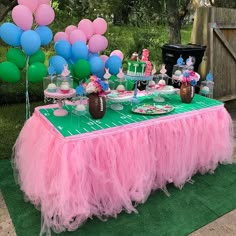 a table topped with lots of balloons and cake on top of a green table cloth