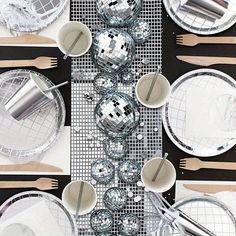 the table is set with silver plates and silver utensils on top of it