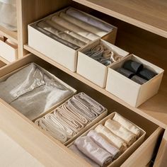 an organized drawer with folded linens and other items in the bins for storage