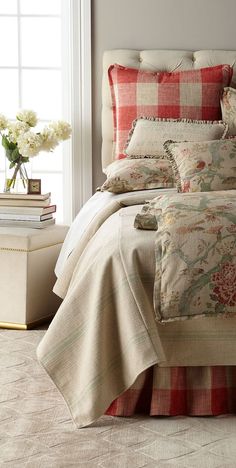 a bed with red and white comforter next to a window