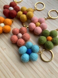 several different colored pom poms on a wooden surface with gold rings and key chains