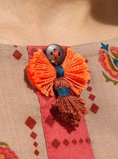 a close up of a woman's blouse with a button and tassel on it