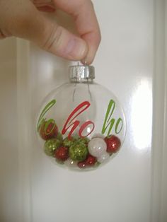 a hand is holding a glass ornament with the word oh on it and ornaments