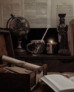 an open book on a table next to a candle and other items in a box