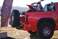 a red truck parked on top of a dry grass field