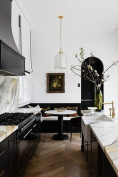 a kitchen with marble counter tops and black cabinets, along with an oval dining table