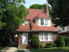 a brick house with white windows and red roof