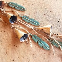 three bells with feathers hanging from them on a piece of wood