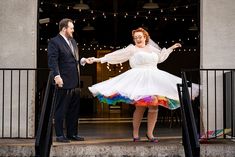 a man and woman dressed up in wedding attire standing on steps with their arms outstretched