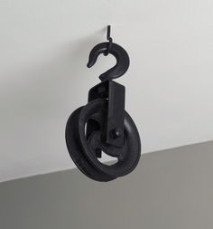 a black object hanging from the ceiling with a hook in it's center and two rings on each end