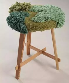 a wooden stool with a green seat cover on it's back and legs that are made out of wood