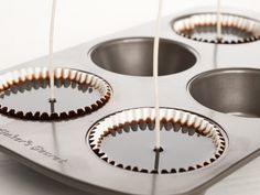 three metal muffin tins being filled with brown and white cupcake liners