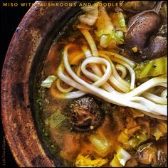 a bowl filled with noodles, mushrooms and broccoli