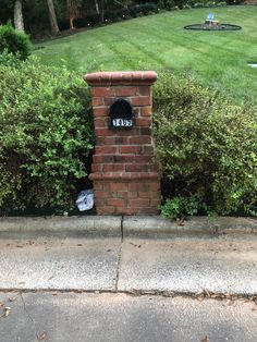 a brick mailbox sitting in the middle of a sidewalk next to a green lawn