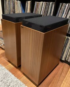 two wooden speakers sitting on top of a hard wood floor next to a record player