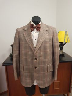 This jacket is from the 1970s in a pure wool and retailed by Fultons Mens wear store. The weight is all season in a light weight fabric from the English west country. Large lapels and flap pockets and two button closure  The condition is very good with no faults found EXCEPT that there is under arm staining in lining . Drycleaning should remove it And a dark mark on the sleeve  as in photo. Measurements are  Shoulder to shoulder 47cm Chest 116cm  Length shoulder to hem 74cm  Sleeves shoulder to Brown Fall Suits With Lapel Collar, Plaid Suits With Pockets For Fall, Fall Plaid Suits With Pockets, Brown Flat Front Suits For Fall, Brown Flat Front Suit For Fall, Tailored Brown Outerwear In Formal Style, Tailored Brown Outerwear, Brown Sport Coat With Suit Collar For Fall, Brown Wool Sport Coat With Suit Collar