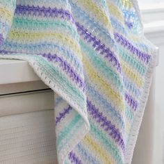 a crocheted blanket sitting on top of a window sill next to a window