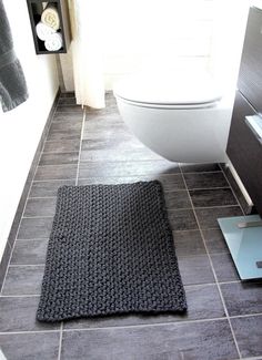 a bathroom with a toilet and rug on the floor