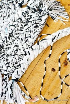 a white and black scarf sitting on top of a wooden floor next to a string