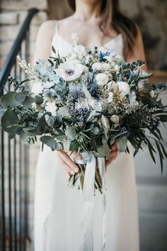 a woman holding a bouquet of flowers in her hands and wearing a white dress on the stairs