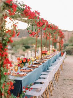 a long table is set up with flowers and candles for an outdoor wedding reception in the desert