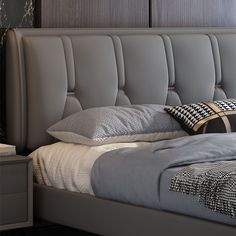 a bed with grey upholstered headboard and two pillows on top of it